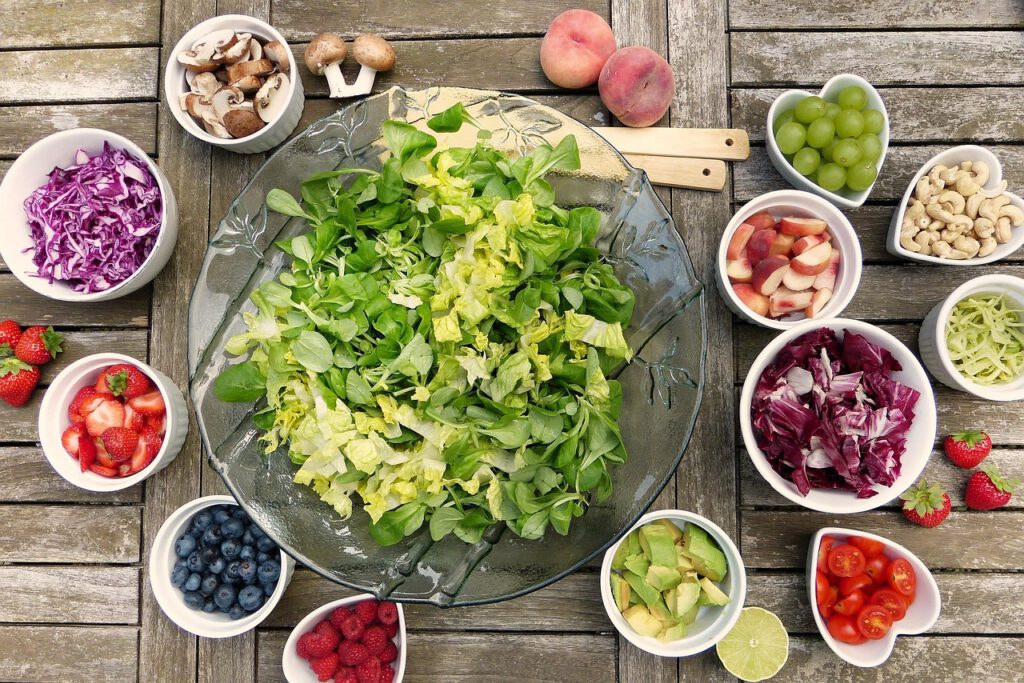 Schalen mit Obst und Gemüse: Grüner Salat, Zwiebeln, Tomaten, Baubeeren, Pilze, Pfirsiche, Himbeeren und noch mehr